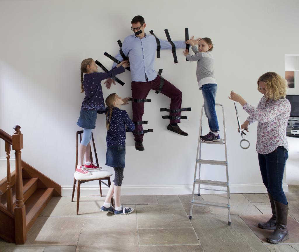 Fun family photography taping dad to the wall